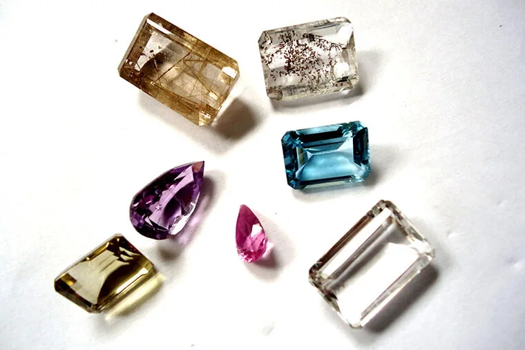 Mixed parcel of faceted coloured gemstones on a sorting tray