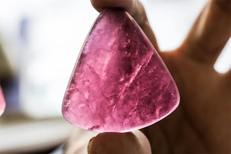 Rough gemstone slice inspected against the light